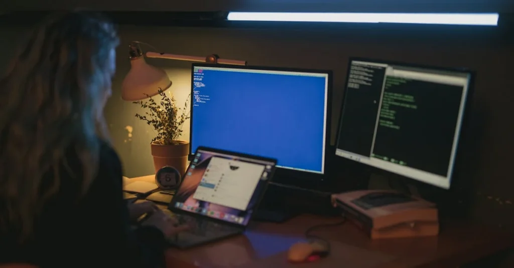 A person with long hair works at a dimly lit desk with two monitors displaying code, a laptop, books, and a potted plant, creating a focused, tech-driven atmosphere.