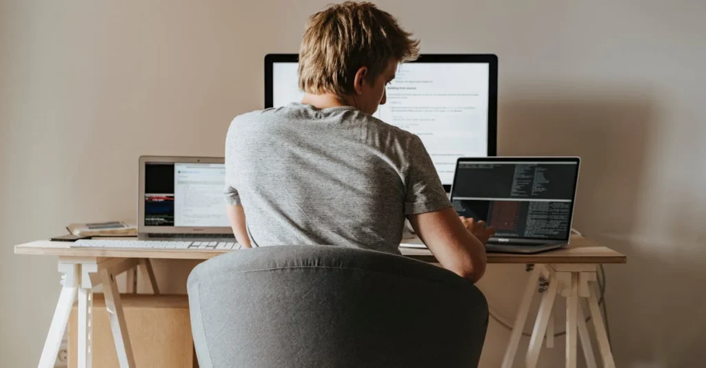 Business analyst reviewing multiple monitors displaying data charts and graphs.