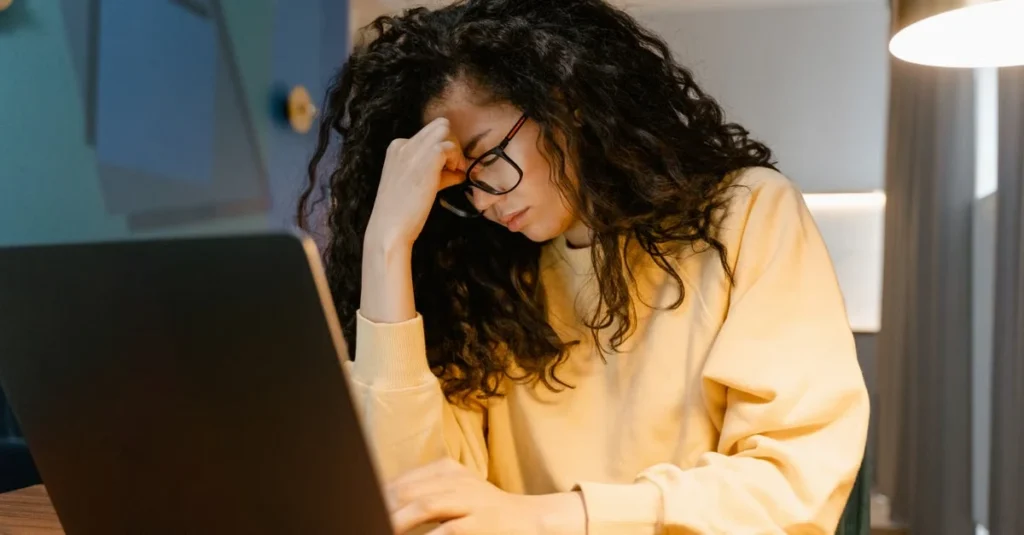 Frustrated online retailer at laptop struggling with ecommerce search engine performance issues during work session.