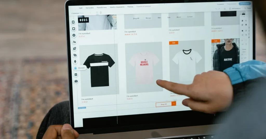 Hand pointing at laptop displaying ecommerce search engine with product grid of apparel items and filters.