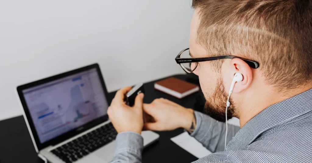 Man with headphones and glasses reviewing Bloomreach software on laptop screen.