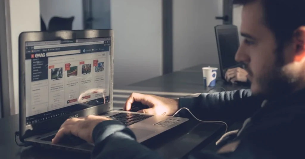 Man using keyboard and mouse browsing semantic search results on laptop screen in office setting.